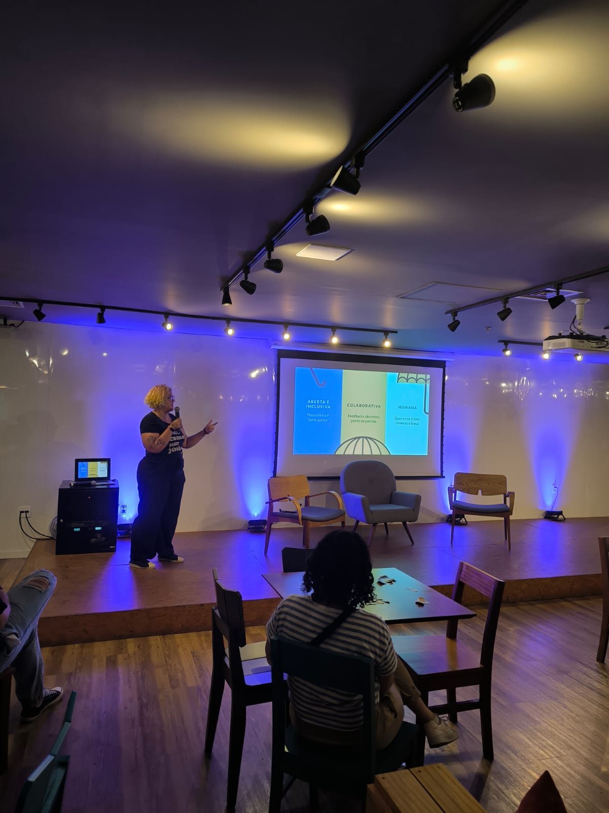 Palestra da VagasUX em um palco com projeção das palavras aberta, colaborativa e humana.