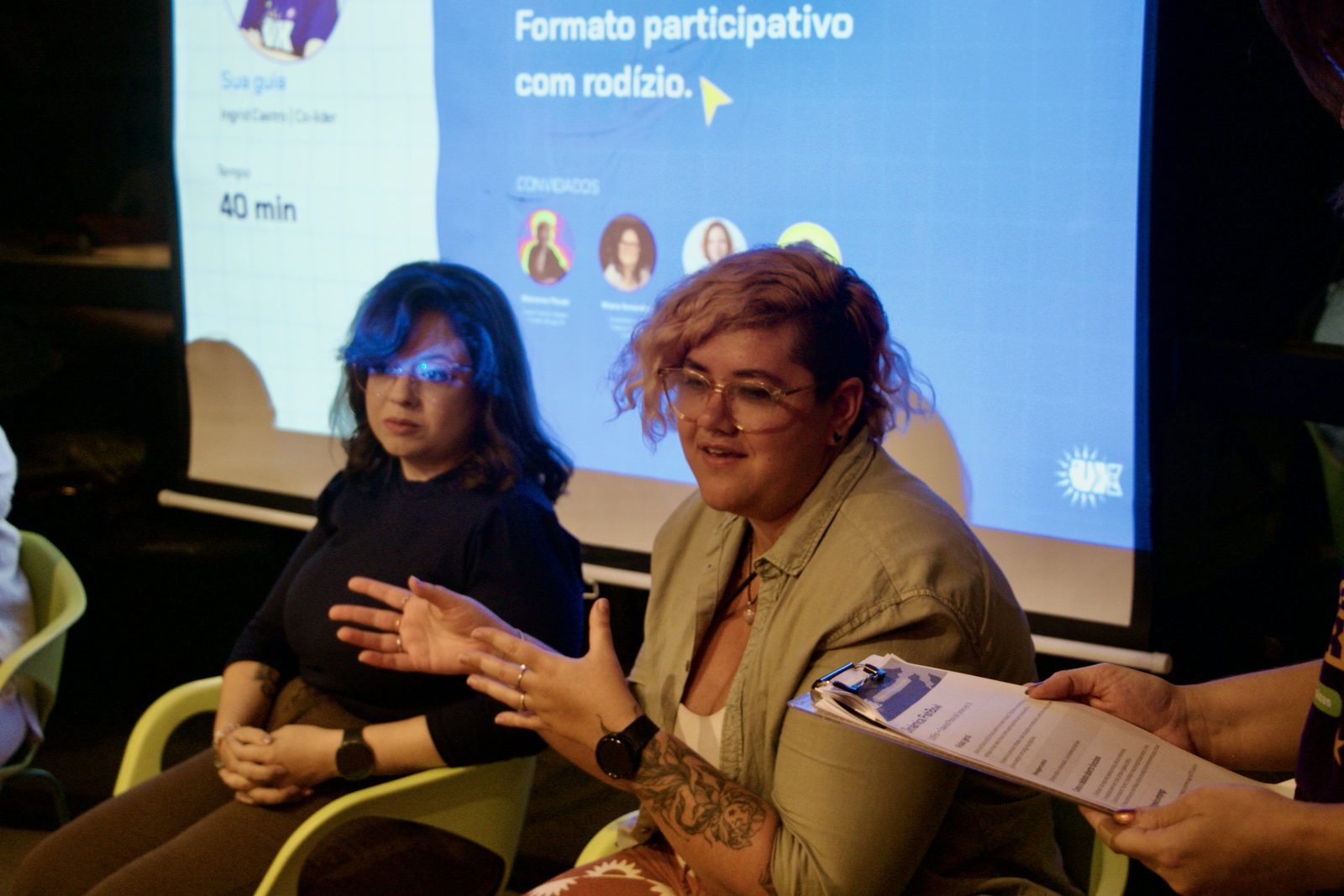 Mesa de conversa da VagasUX com formato participativo em rodízio projetado ao fundo.